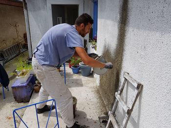 Man throwing cement on house wall