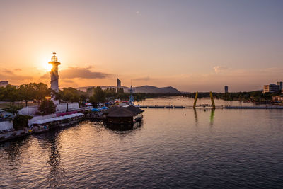 Boats moored in river against sky during sunset