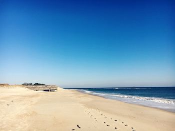 Scenic view of beach against clear blue sky