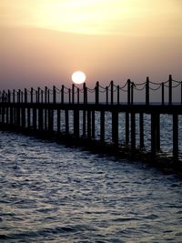 Silhouette pier over sea against sky during sunset