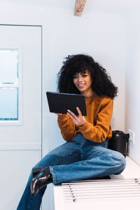 Young woman using digital tablet while sitting on sofa at home
