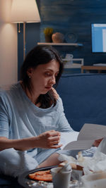 Young woman reading letter sitting at home