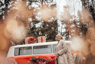 Side view of woman standing by car