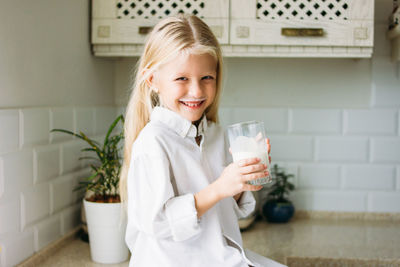 Portrait of smiling girl holding milk in glass
