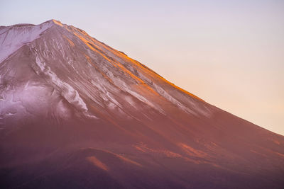 Scenic view of snowcapped mt fuji against clear sky during sunset