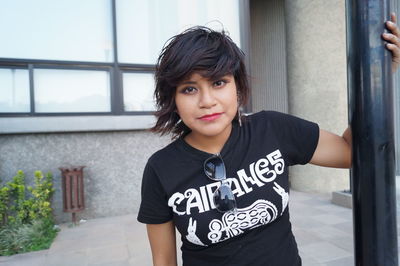 Portrait of smiling young woman standing against wall