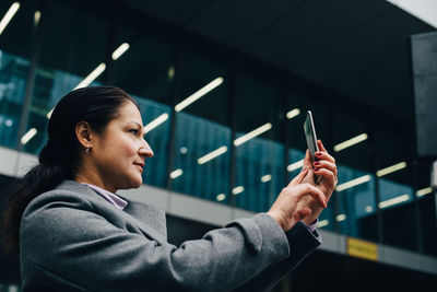 Portrait of young woman looking at illuminated shop