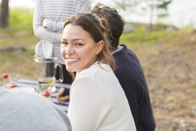 Portrait of happy woman with friends at picnic table