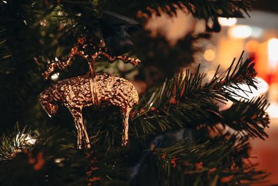 Christmas toy golden lamp hanging on the christmas tree with blurry shiny festive bokeh lights