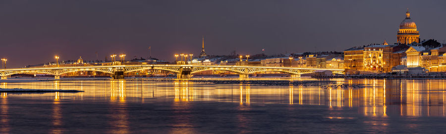 Illuminated bridge over river at night