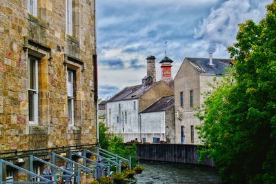 Buildings by river against sky