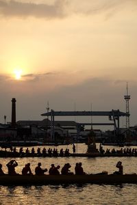 Silhouette people on boat in river against sky during sunset