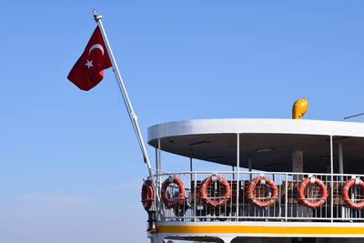 Low angle view of flags against clear blue sky