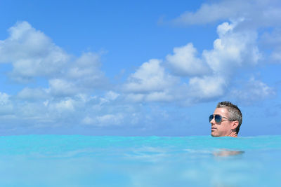 Mature man swimming in sea against cloudy sky