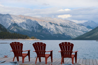 Chairs and table on snowcapped mountains against sky