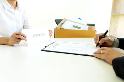 Midsection of woman reading book on table