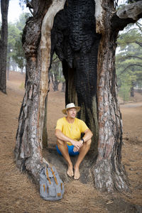 Rear view of woman sitting on tree trunk