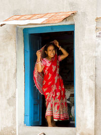 Portrait of smiling woman wearing sari at doorway in village