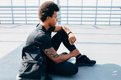 Side view of young man sitting on bridge