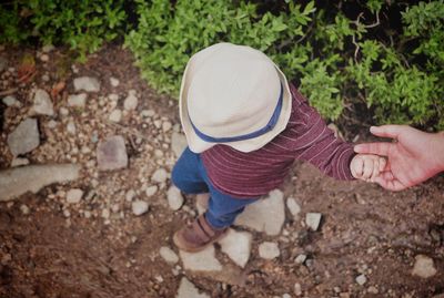 Small boy holding woman hand while hiking