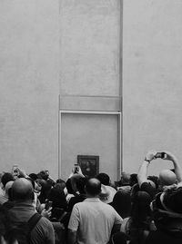 Rear view of people looking through wall