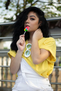 Portrait of beautiful woman holding yellow while standing outdoors
