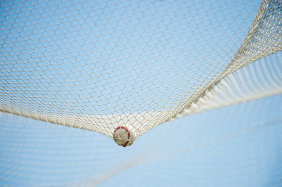 Close-up of ball in net against sky on court