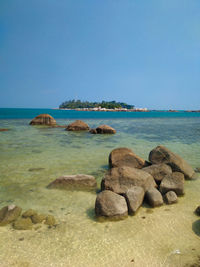 Rocks on beach against clear blue sky