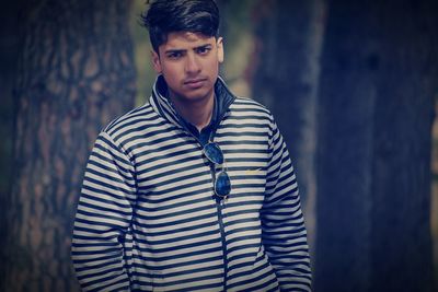 Portrait of young man standing in forest