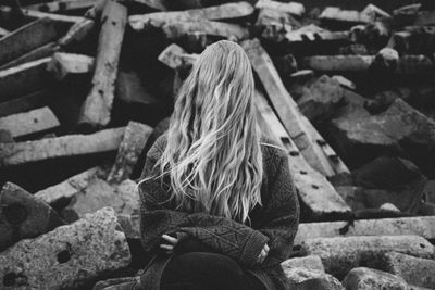 Woman sitting on rock covering face with hair