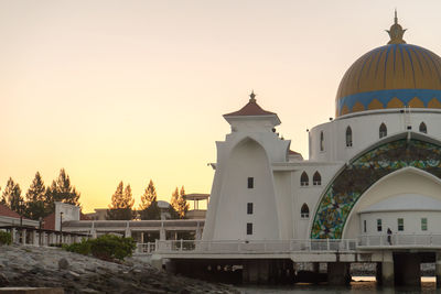 Mosque at beach against sky during sunset