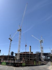 Cranes at construction site against clear blue sky
