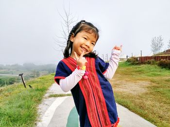 Portrait of happy girl standing against clear sky