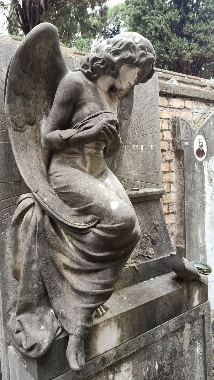 CLOSE-UP OF ANGEL STATUE AGAINST OLD BUILDING