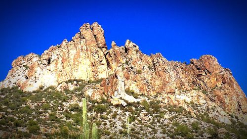 Low angle view of rock formation against clear blue sky