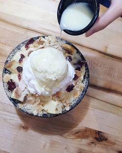 Cropped image of hand pouring cream on dessert