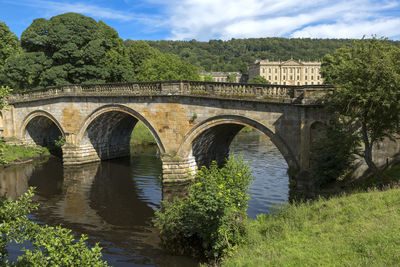 Arch bridge over river against sky