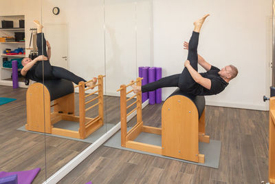 Male fitness pilates trainer shows exercises on special simulators. pilates stretch tables