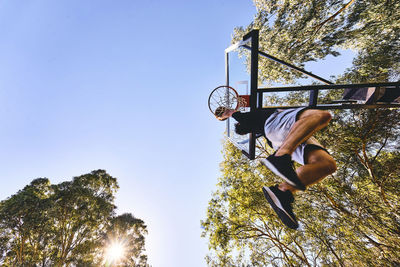 Low angle view of man playing basketball against clear sky