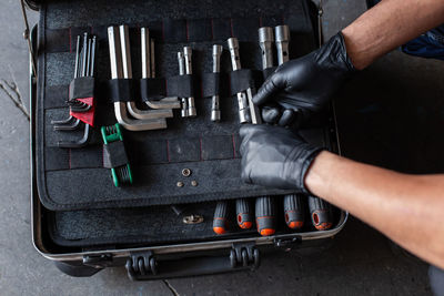 From above unrecognizable male technician picking screwdriver bits from tool box while working in garage