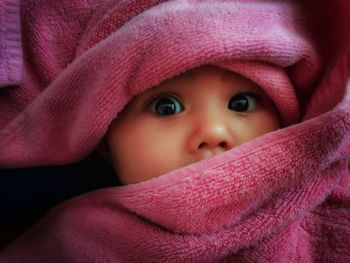 Close-up portrait of cute baby girl wrapped in towel