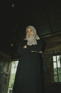 Portrait of young woman standing in abandoned room