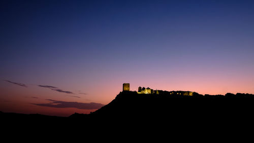 Silhouette buildings against clear sky at sunset