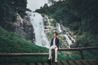 Woman standing on rock against waterfall