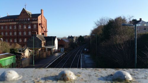 Railroad tracks amidst buildings against clear sky