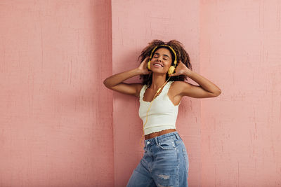 Portrait of young woman standing against wall