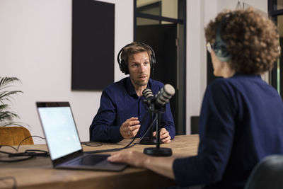 Man wearing headset talking with guest in recording studio