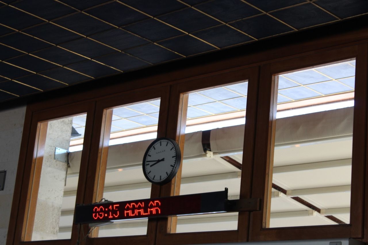 clock, time, no people, indoors, instrument of time, window, number, day, architecture, low angle view, glass - material, built structure, accuracy, minute hand, clock face, communication, text, clock hand, transparent, hour hand, wall clock