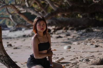 Portrait of young woman sitting on shore at beach