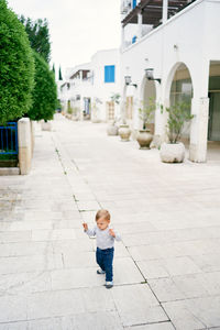 Boy standing on footpath against building